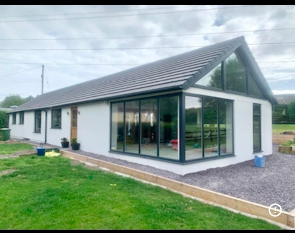 White rendered extension with corner window and wooden door