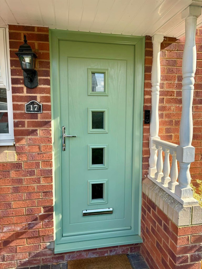 Sage green front door with glazed panels on red brick